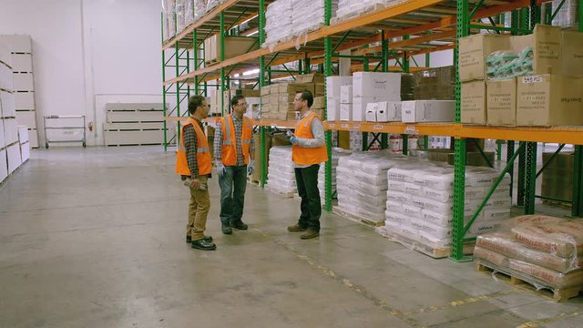 WS DS TS Three workers walking and talking in Warehouse, Drywall with one holding tablet