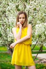 Fototapeta na wymiar Young girl posing near blossom cherry tree with white flowers