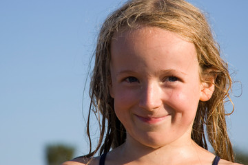 Blondes lächelndes Mädchen mit nassen Haaren in der Sonne