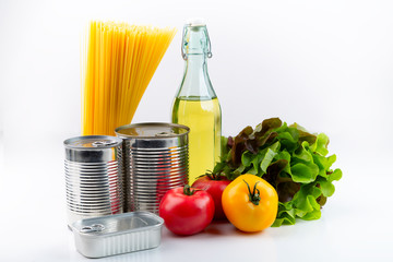 Canned foods, pasta, fresh vegetables, butter and a fresh salad. The concept of food delivery, storage or donation. On a light background. Front view. Horizontal.