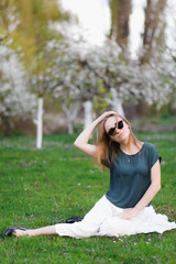 Obraz premium Girl in sunglasses sits in a cherry garden