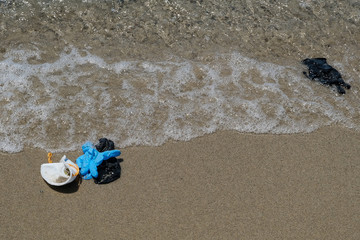 Fototapeta na wymiar Protective virus masks and plastic gloves garbage trash on sandy sea shore,coronavirus covid pollution disease 