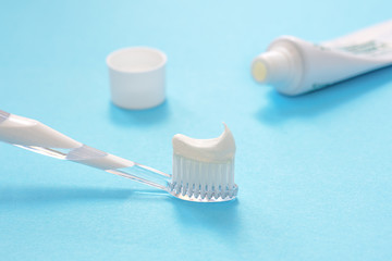 white toothbrush with toothpaste on a blue background, close-up