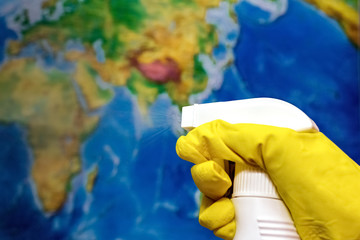 Hand sanitazer spray cleans the earth map (in defocus) Metaphor for saving environment, ecology activity. Protecting world from Coronavirus. Using disinfectant spray.