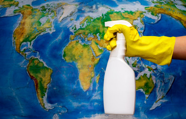 Hand sanitazer spray cleans the earth map (in defocus)Metaphor for saving environment, ecology activity. Concept: Ecology, environmental protection, fighting pandemic Covid 19.