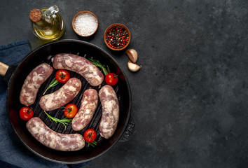 raw sausages in a pan with spices and rosemary on a stone background with copy space for your text