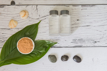 Spa cosmetics set. Lotion and marocan clay on a green leaf. Copyspace for text. Top view. Flatlay on wooden background.
