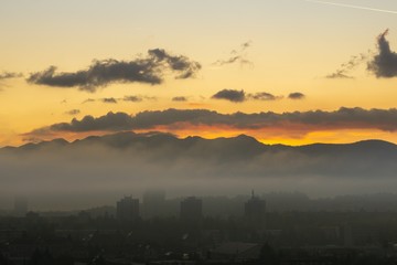 Sunrise and sunset, beautiful clouds over the meadow, hills and buildings in the town. Slovakia