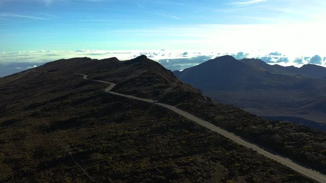 Aerial following a lone vehicle as it traverses the Haleakalā Crater summit drive and surrounding vista