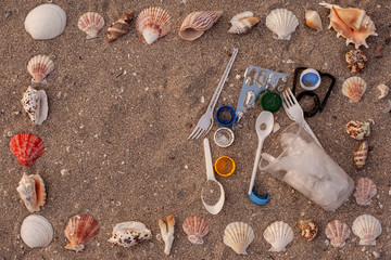 Concept of choice: used plastic straws on background of dirty sand beach and shells. Plastic ocean pollution, environmental crisis. Say no plastic. Single-use plastic waste
