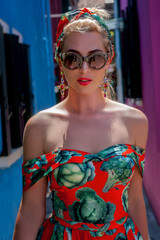 elegant, fashionable girl with glasse stay in the street , in a romantic Burano,Italy