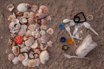 Concept of choice: used plastic straws on background of dirty sand beach and shells. Plastic ocean pollution, environmental crisis. Say no plastic. Single-use plastic waste