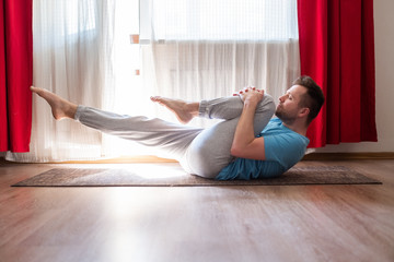 man doing yoga on floor, practicing Supported One Legged Wind Relieving Pose