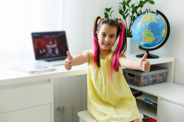 Cool online school. Kid studying online at home using a laptop. Cheerful young little girl using...