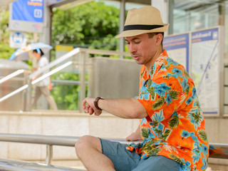Young handsome tourist man checking the time at the subway station outdoors