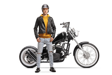 Fototapeta na wymiar Young man biker in a leather jacket posing next to his motorbike