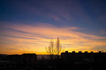 Sunrise and sunset, beautiful clouds over the meadow, hills and buildings in the town. Slovakia