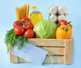Set of food in a wooden box on a blue background,copy space. Coronavirus Relief Funds and Donations.Сoncept of safety mail goods courier delivery in virus or coronavirus quarantine.