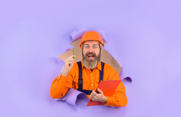 Through paper. Advertising. Repair. Building concept. Engineer making notes. Repairman with folder. Construction worker with folder. Repairman with folder. Man in hard hat. Helmet.