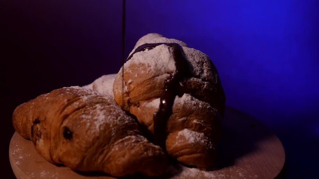 Croissants rotating with powdered sugar and chocolate syrup