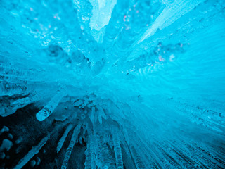 Blue ice background. Ice stalactites stalagmites. The ice of lake Baikal