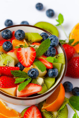 Concept of low calories delicious desserts. Summer fresh bowl with colorful fruit salad. Healthy natural organic food. Tasty sweet snack, light simple tasty lunch. Close up macro view white background