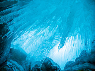 Blue ice background. Ice stalactites stalagmites. The ice of lake Baikal