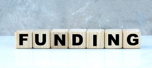 concept of the word FUNDING on cubes on a gray background