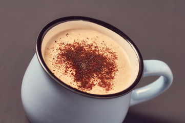 Blue mug of coffee with foam on concrete surface. Concept of love or christmas. Toned and vintage image