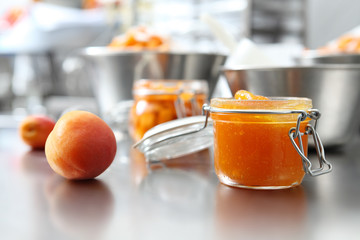 Jam from apricots in a glass jar on a polished stainless steel surface in pastry professional...