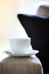 Fototapeta na wymiar Tea cup and saucer on sofa armrest