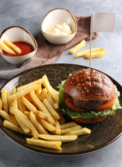 American cuisine. Fast food. French fries with ketchup and mayonnaise and hamburger. Fresh basil. Background image, copy space