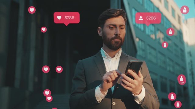 Wonder handsome young man uses smartphone typing social media icons with like comment follower counter stand on street at sunlight close up slow motion