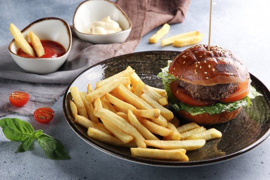 American cuisine. Fast food. French fries with ketchup and mayonnaise and hamburger. Fresh basil. Background image, copy space