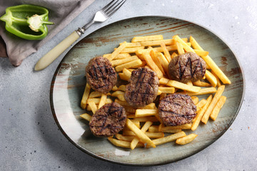 Fast food. Potatoes with fried beef patties cutlet on a plate on a light grey background. French fries. Background image, copy space