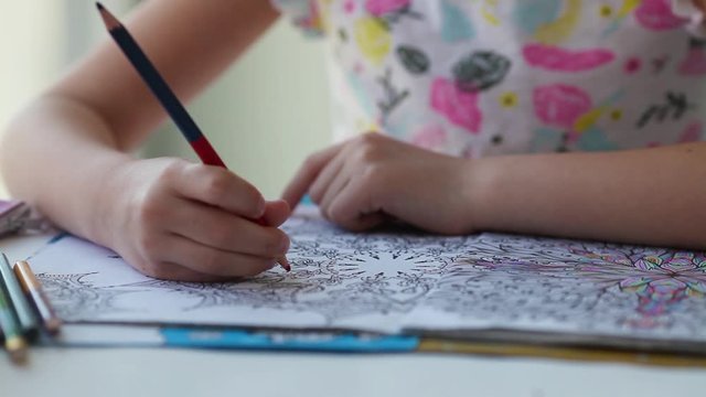 Antistress coloring page. Child  hand paints a coloring book for adults with crayons.