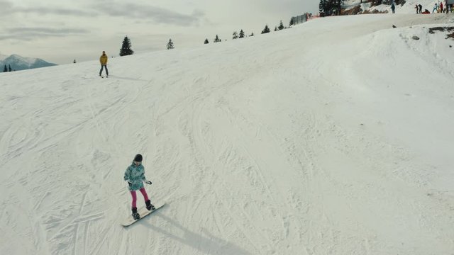 Woman in pink trousers and man skiing down the hill filmed from the front