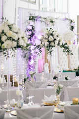 Tables for wedding party decorated with flowers, greenery and candles