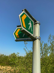 Signpost in the countryside showing a walking route for pedestrians. No people.