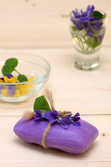 Obraz na płótnie Canvas bar of purple soap and flowers violets on the table