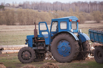 Fototapeta premium An old blue tractor stands in the backyard of a farm