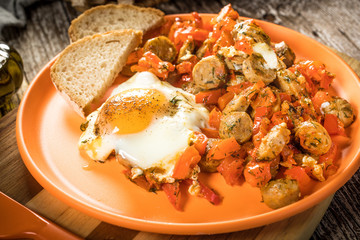 Fried vegetables with sausage and fried egg.
