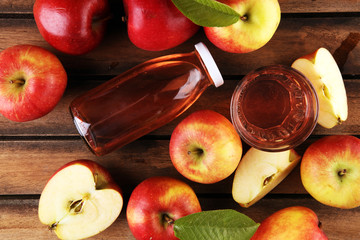 Apple cider drink and organic apples with leaves on table