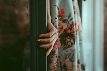 a close-up view of a female hand touching a green door. Woman entering the room and pulling the door. Pink manicure on green wooden door. Elegant and aesthetic shot. Safety or beauty concept.