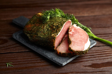 Polendwitz is a jerky tenderloin, dried pork with spices and fresh green dill, slate cutting board on brown table. Cured filet