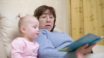 grandmother shows granddaughter a children's book, selective focus on woman, close up