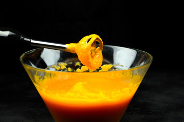 Pumpkin puree with blender in transparent bowl on black background. Cooking mashed pumpkin