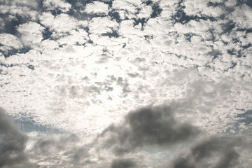 Gray sky after rain with white clouds through which the sun's rays break through. Monochrome. Concept landscape, abstraction.