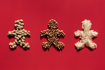Three little men made of lentils, rice and buckwheat on a red background