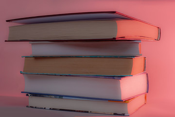 stack of various books in red light. pile of different hardback books. Prose, poetry, novels, detective stories and historical literature. The concept of reading, study and knowledge